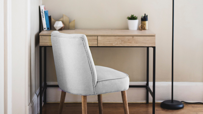 Brightly lit remodelled basement with a wooden desk and an upholstered chair.